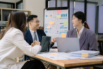 Asian business corporate team brainstorming, planning strategy having a discussion Analysis investment researching with chart at office desk documents in office.