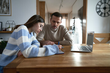 Caucasian father with teenager daughter make homework at home