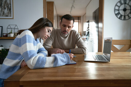 Caucasian father with teenager daughter make homework at home - Powered by Adobe