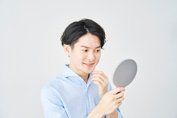 ハンドミラーで顔を見る男性　白背景