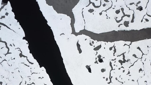 Birds-eye view drone shot tracking the meanders of the snowy Gress river on the Outer Hebrides of Scotland.