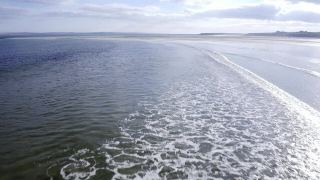 Low flying drone shot of the waves breaking at Gress beach on a sunny day in the Outer Hebrides of Scotland.
