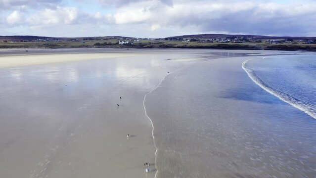Panning drone shot of the waves at Gress beach at low tide on the Outer Hebrides of Scotland.