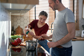 Caucasian man cooking with teenager daughter at home