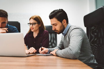 Group of three young business people having a meeting in a bright white office 