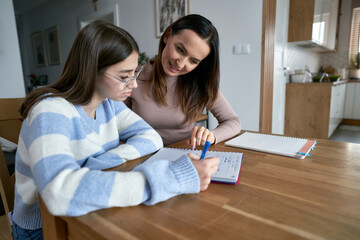 Caucasian mother with teenager daughter make homework at home