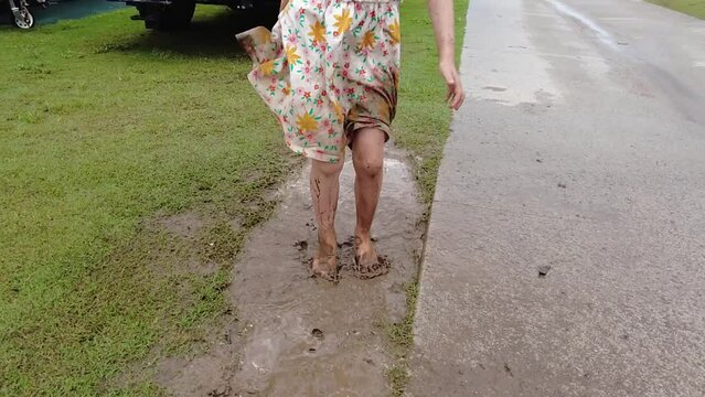 Unrecognizable Young Little Girl With Dress Jumping in Mud Puddle, Slow Motion
