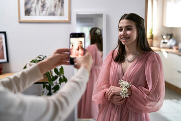 Young girl posing to pictures of her mother before the prom