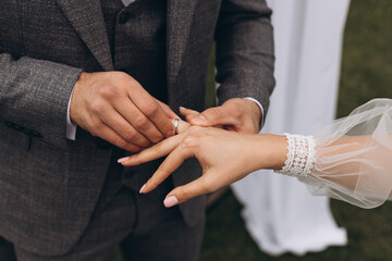 Groom in a Gray Jacket Puts a Ring on a Bride, Close-Up Shot