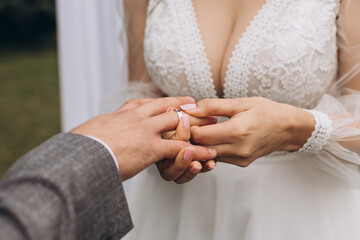 Bride in a White Dress Puts a Ring on Groom in a Gray Jacket, Close-Up