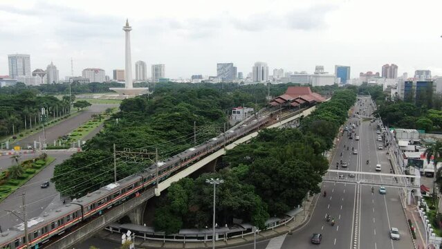 Beautiful view with drone of the National Monument under the blue sky with a train running into gambir station in Jakarta, Indonesia