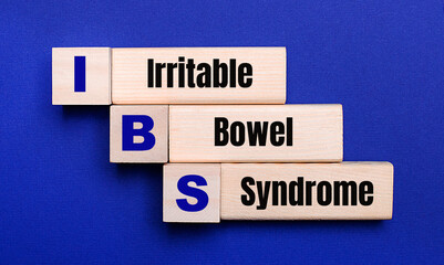 On a bright blue background, light wooden blocks and cubes with the text IBS Irritable Bowel Syndrome