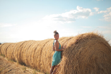 Naklejka na ściany i meble young beautiful woman leaning against a bale of hay