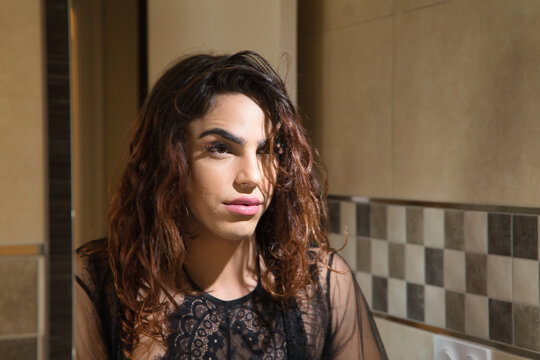 Young transgender girl, looking at herself in the mirror after having make up, with serious and worried gesture. Concept transgender, lgtbi, homosexuality, gay, diversity.