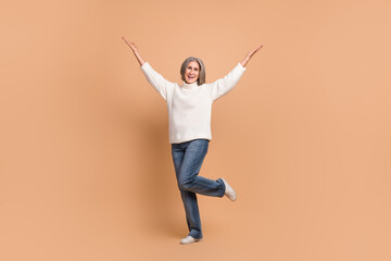 Fototapeta na wymiar Full length photo of pretty funky lady dressed white sweater rising arms catching empty space isolated beige color background