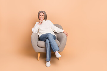 Fototapeta na wymiar Full length photo of dreamy thoughtful lady dressed white sweater sitting sofa arm chin isolated beige color background