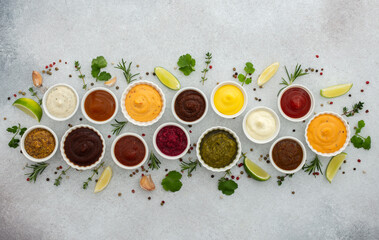 Different types of sauces in bowls with seasonings, rosemary and pepper, thyme and garlic, lime and lemon, cilantro, top view, copy space