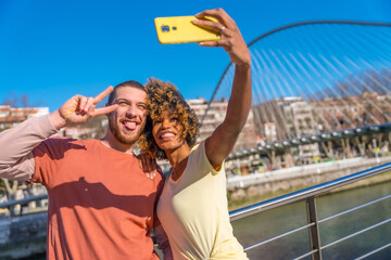 Multiracial couple through the city streets, lifestyle, selfie smiling by the river