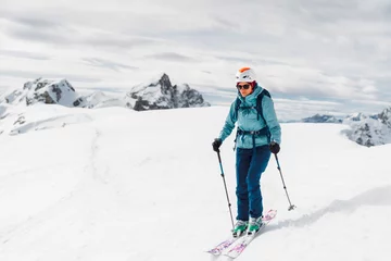 Fotobehang Portrait of a ski tourer in blue ski jacket and white helmet, ready to ski down the mountain © VisualProduction