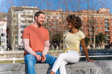 Multiracial couple on the city street, lifestyle, sitting smiling talking on the weekend
