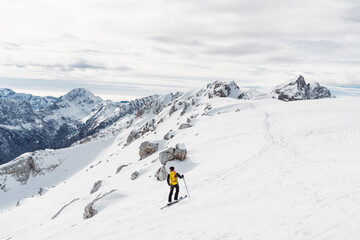Naklejka na ściany i meble One lonely ski tourer skiing down the snowy mountain 
