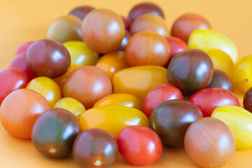 Cherry tomatoes in a variety of bright colors on an orange background.