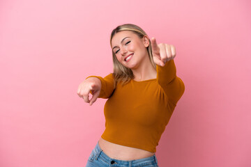 Young caucasian woman isolated on pink background pointing front with happy expression