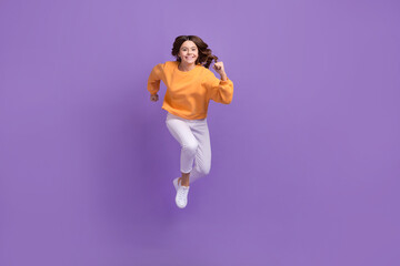 Fototapeta na wymiar Full body portrait of energetic overjoyed girl jumping rush isolated on purple color background