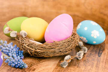 Easter eggs in a nest with spring flowers on wooden background. Easter concept