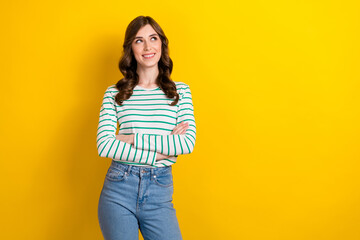 Photo portrait of pretty young girl folded arms look curious empty space wear trendy striped clothes isolated on yellow color background