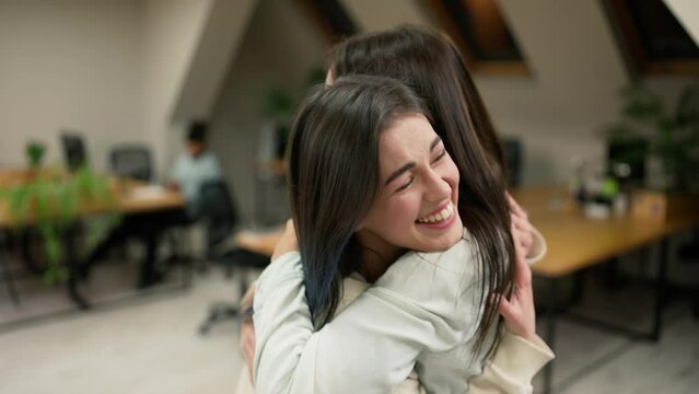 Young female office workers hugging to congratulate a colleague or missing a friend from vacation