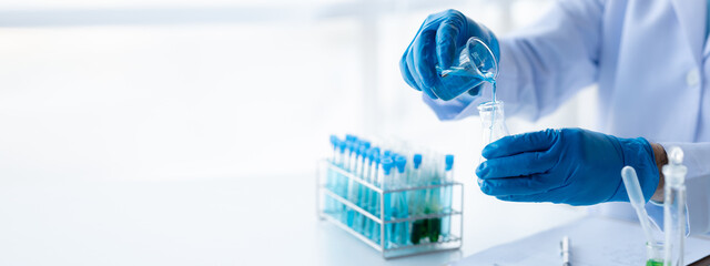 Lab assistant, a medical scientist, a chemistry researcher holds a glass tube through the blood sample, does a chemical experiment and examines a patient's blood sample. Medicine and research concept.