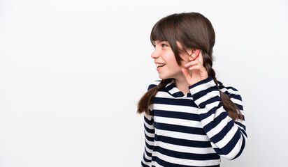 Little caucasian girl isolated on white background listening to something by putting hand on the ear