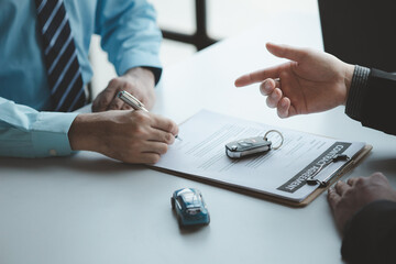 A car salesman is explaining the purchase details and details in the car purchase contract before signing acceptance of the terms, the car sales contract through an agent. Car trading concept.