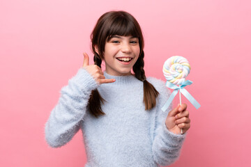 Little caucasian girl holding a lollipop making phone gesture. Call me back sign