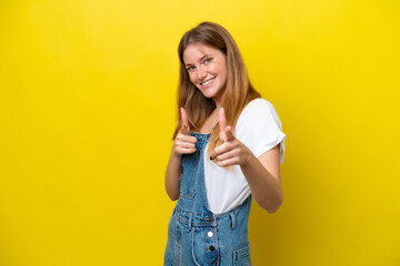 Young caucasian woman isolated on yellow background pointing to the front and smiling