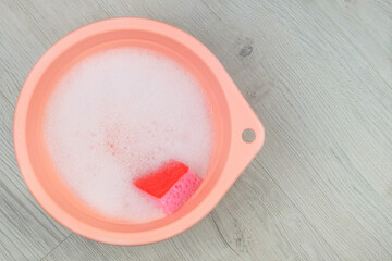 Detergent with washcloths on a wooden background. Washing in a pink basin. Top view.