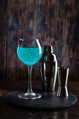 Bright turquoise cocktail and shaker. Cocktail on the bar. Shaker and jiger on the bar. Prepared cocktail.