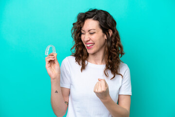 Young caucasian woman holding a envisaging isolated on blue background celebrating a victory