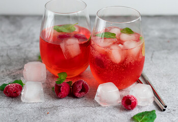 Cool cocktail with ice and mint and raspberry. On a gray background. Summer.