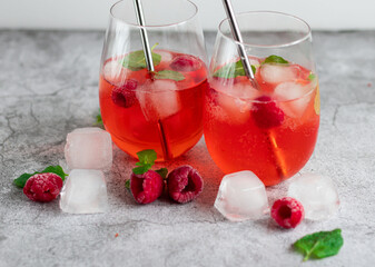 Cool cocktail with ice and mint and raspberry. On a gray background. Summer.