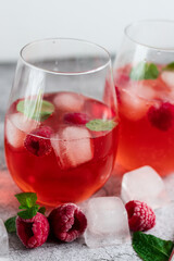 Cool cocktail with ice and mint and raspberry. On a gray background. Summer.