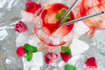Cool cocktail with ice and mint and raspberry. On a gray background. Summer.