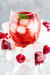 Cool cocktail with ice and mint and raspberry. On a gray background. Summer.