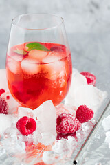 Cool cocktail with ice and mint and raspberry. On a gray background. Summer.