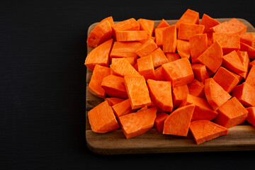 Raw Chopped Sweet Potatoes on a Cutting Board, side view. Space for text.