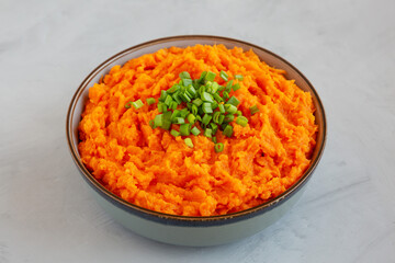 Homemade Creamy Mashed Sweet Potatoes with MIlk and Butter in a Bowl on a gray background, side view.