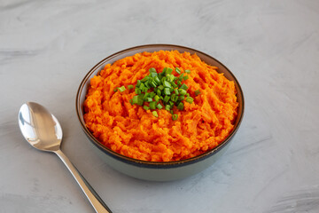 Homemade Creamy Mashed Sweet Potatoes with MIlk and Butter in a Bowl on a gray background, side view.