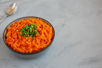 Homemade Creamy Mashed Sweet Potatoes with MIlk and Butter in a Bowl on a gray background, side view. Space for text.