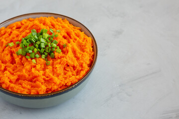 Homemade Creamy Mashed Sweet Potatoes with MIlk and Butter in a Bowl on a gray background, side view. Copy space.